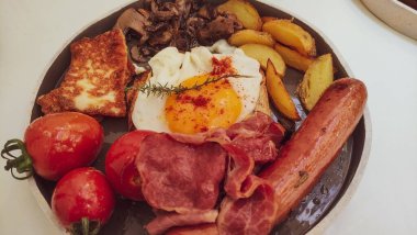 Sağlıklı ve dengeli kahvaltı tabağı. Yumurta, patates, sosis, domuz pastırması ve peynir de dahil. Izgara peynir ve sosis tabağı. Yukarıdan bakınca sağlıklı bir kahvaltı..