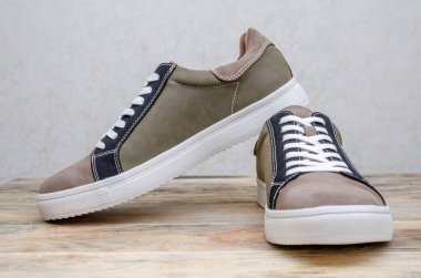 Yeni moda gri-yeşil erkek ayakkabıları beyaz tabanlı ve tahta arka planda beyaz bağcıklar.