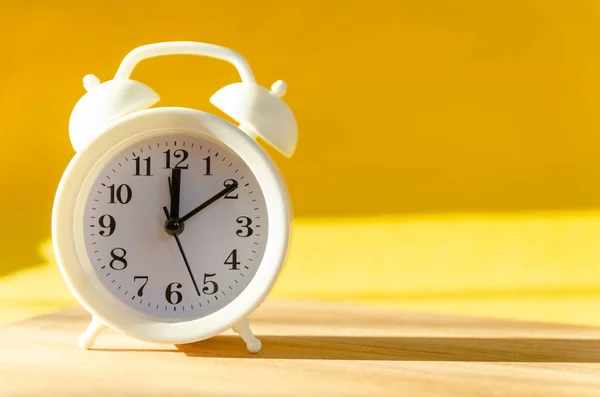 Relógio Alarme Branco Fica Uma Mesa Madeira Fundo Amarelado Sob — Fotografia de Stock