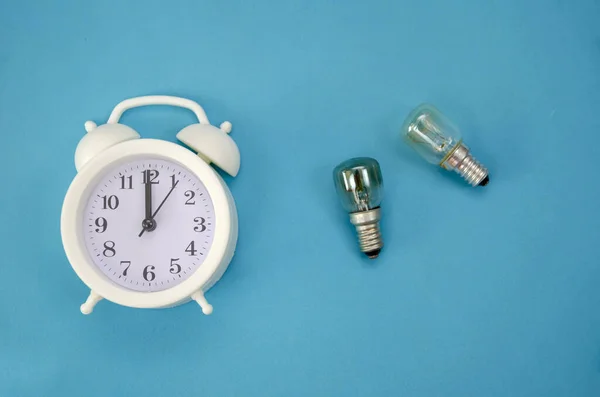 Reloj Despertador Blanco Sobre Fondo Azul Con Dos Bombillas Vidrio —  Fotos de Stock