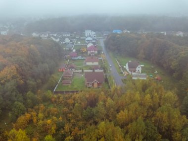 Köy evlerinin tepeden aşağı manzarası, bulutlu havada sisli güzel sonbahar ormanı, İHA 'dan çekilmiş bir fotoğraf..