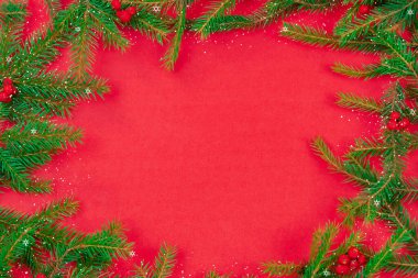 Kırmızı Rowan böğürtlenli Noel ağacı dalları, Baka, kırmızı arka planda fotokopi alanı olan kar, üst manzara. Noel ve yeni yıl için tebrik kartı. Güzel Noel arkaplanı.