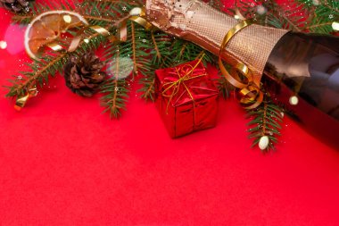 Noel ağacı, şampanya, kırmızı hediye kutusu, röfle, kırmızı arka planda kırmızı bir portakal ve fotokopi alanı. Güzel, aydınlık Noel, yeni yıl geçmişi