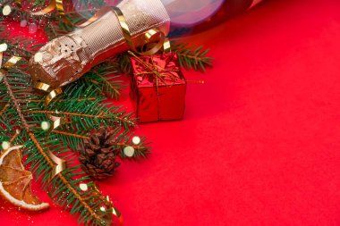 Noel ağacı, şampanya, kırmızı hediye kutusu, röfle, kırmızı arka planda kırmızı bir portakal ve fotokopi alanı. Güzel, aydınlık Noel, yeni yıl geçmişi