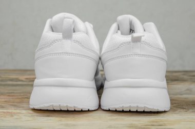 Ahşap bir arka planda güzel bir çift beyaz kadın ayakkabısı. Yakın plan. Spor ayakkabısının topuk kısmı yakın.