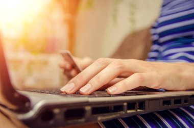 Kredi kartı tutan ve dizüstü bilgisayar kullanan bir kadının ellerinin yakın çekimi. Çevrimiçi alışveriş kavramı