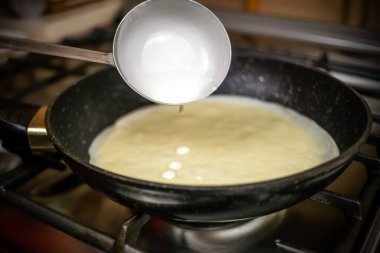 Krep hamuru yakın mesafeden tavaya dökülüyor. Mangırla kepçeye odaklan.