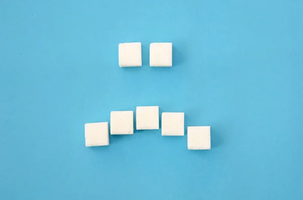 Cubos Açúcar Branco Dispostos Forma Sorriso Triste Fundo Azul Close — Fotografia de Stock