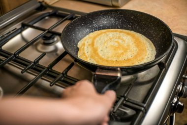 Kadının eli siyah bir tavayı yakın planda tutuyor. Kahvaltı konsepti