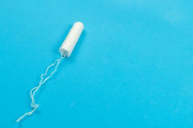 Fotokopi alanı olan mavi bir arka planda tıbbi kadın tamponu. Kadınlar için hijyenik beyaz tampon. Regl, bir koruma aracı..
