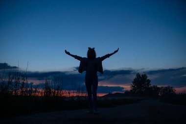 Güzel mavi bir günbatımı gökyüzüne karşı elleri havada bir kızın silueti. Güzel arkaplan, doğa, duvar kağıdı.