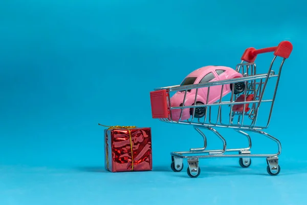 Wózek Sklepowy Różową Maszyną Pisania Środku Niebieskim Tle Czerwonym Pudełkiem — Zdjęcie stockowe