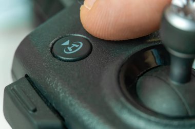 İnsanoğlunun eli insansız hava aracının uzaktan kumandasındaki ev tuşuna basar. Ev.