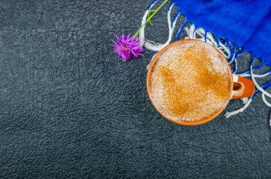 Tarçınlı kahve fincanı kapuçino, mavi atkı, siyah arka planda fotokopi alanı, üst manzara, düz yatak. Güzel sonbahar kompozisyonu, güzel arka plan.