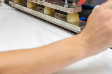 Erkeklerin elleri makinede PVC film ve kenar dikişler için çalışıyor. Gergin tavan üretimi için dükkan..