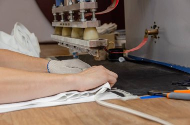 Erkeklerin elleri makinede PVC film ve kenar dikişler için çalışıyor. Gergin tavan üretimi için dükkan..