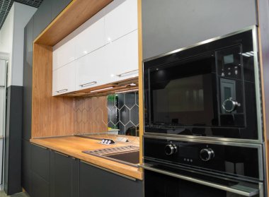 Gri ve ahşap tonlarda ev aletleriyle modern bir mutfağın güzel, minimalist iç mimarisi.