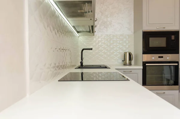 Beautiful interior of a classic kitchen in light gray and white colors with led lighting