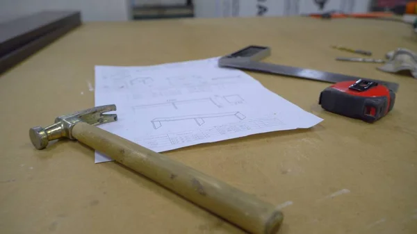 Tools on the table. Woodworking workshop. On the table are a hammer, marker, tape measure, drawing and corner. Close up.