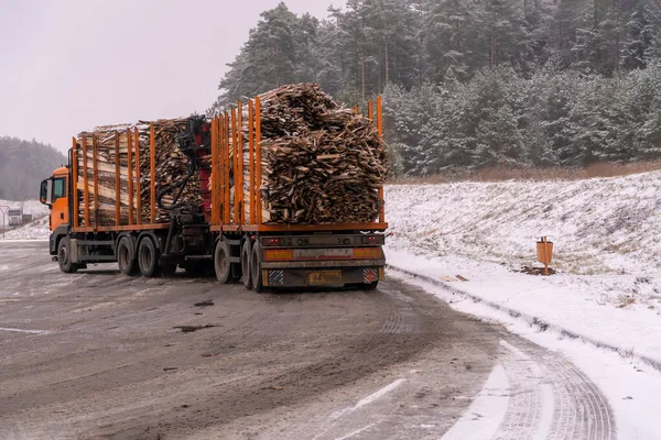 Big truck transports raw picket fence, firewood on winter snow day