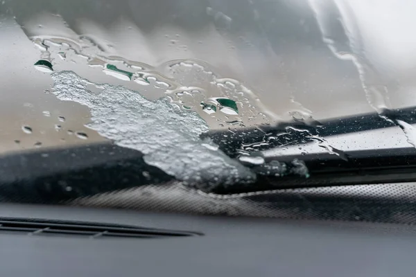 Thawed ice on the windshield of the car near the wipers in wet, slushy weather. photo from inside the car