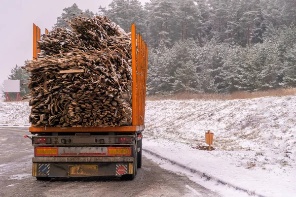 Big truck transports raw picket fence, firewood on winter snow day