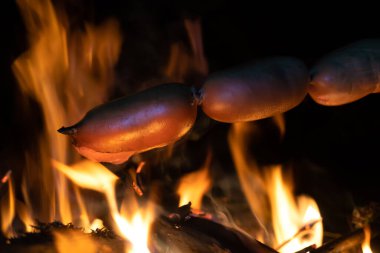 Geceleri ateşte sosis pişirmek. Geceleri doğada odun çubuklarda kamp ateşi yakmak..