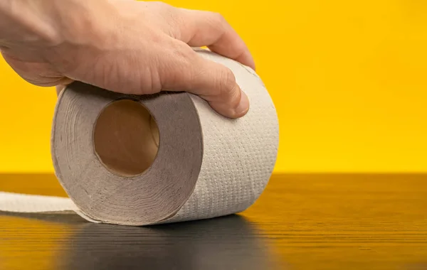 Erkek Sarı Arka Planda Tuvalet Kağıdı Rulosunu Alır — Stok fotoğraf