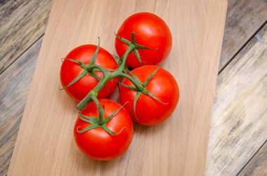 Taze, olgun, sulu, kırmızı domatesler, bir dalın üzerinde yakın plan, masanın üzerinde tahta bir sopa, üst görüş