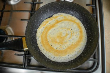 Krep, gaz sobasının üstünde siyah bir tavada kızartılıyor. Kahvaltı konsepti