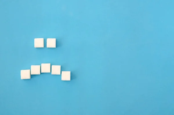Cubos Açúcar Branco Dispostos Forma Sorriso Triste Fundo Azul Close — Fotografia de Stock