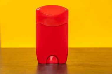 Sarı zemin üzerinde deodorant bulunan kırmızı kap, boşluğu kopyala