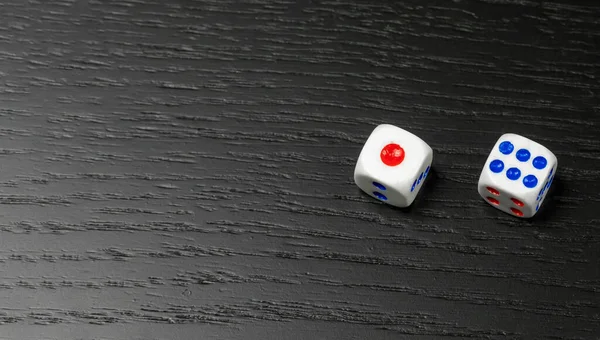 黑色背景上带有蓝点和红点的带复制空间的骰子 — 图库照片