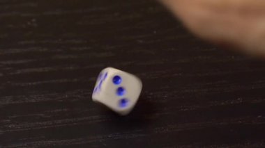 Tahta masanın üzerindeki el zarları döndürür. Yakın plan.