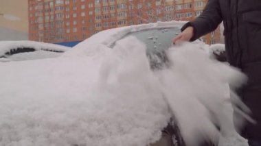 Bir kadın kar fırtınasından sonra arabayı temizler..