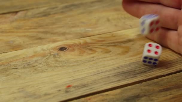 Ręka rzuca dwie kości na drewniany stół. Zbliżenie — Wideo stockowe
