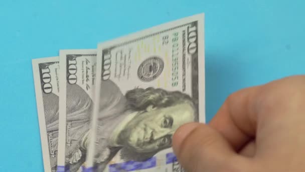 De hand van een man legt 100 dollar biljetten op tafel.. — Stockvideo