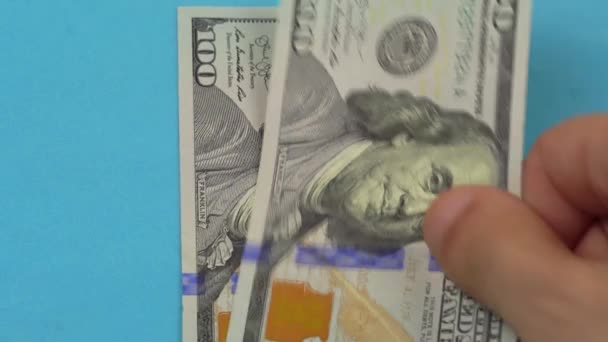 De hand van een man legt 100 dollar biljetten op tafel.. — Stockvideo