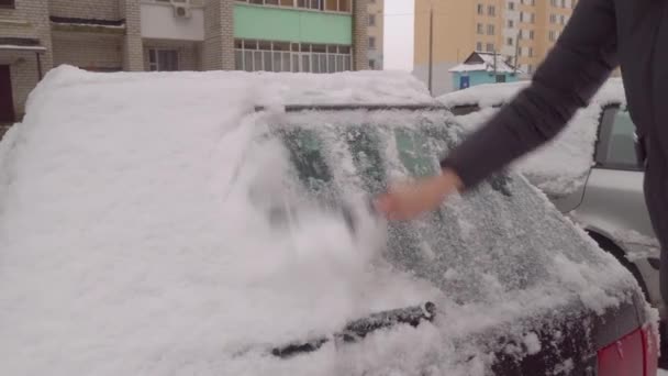 一个女人在暴风雪之后用刷子把车从雪地上擦干净. — 图库视频影像