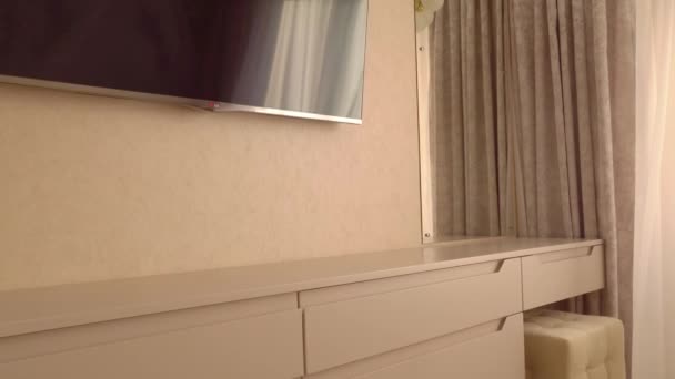 Mogilev, Weißrussland-13. August 2020: LG-Fernseher und Regal vor einem einfachen, bequemen Doppelbett, das an einem sonnigen Tag in einem modernen Schlafzimmerinterieur in Sonnenlicht getaucht ist. Ohne Menschen in 4K — Stockvideo