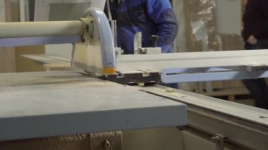 Bir adam kesme makinesinde ahşap bir levha kesiyor..