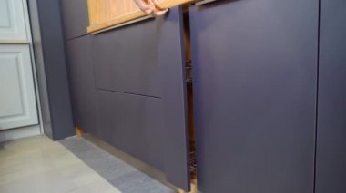 Bir kadın bulaşık yıkamak için mutfak dolabını açıyor..