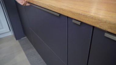 Mutfak dolabında bir kadın çekmece açıyor.