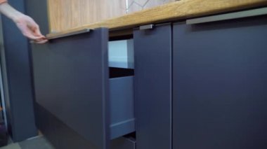 Mutfak dolabında bir kadın çekmece açıyor.