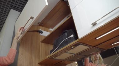 Bir kadın bulaşık yıkamak için mutfak dolabını açıyor..