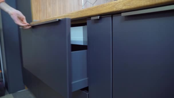 Uma mulher abre uma gaveta no armário da cozinha — Vídeo de Stock