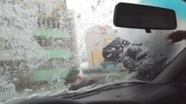 Žena škrábe led z předního skla svého auta po dlouhé parkoviště. — Stock video