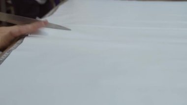 Bir kadın, gerilme tavanı üretimi için dükkanda PVC film kesiyor.