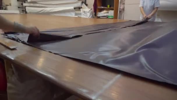 Жінка розгладжує ПВХ плівку в магазині для виробництва натяжних стель — стокове відео