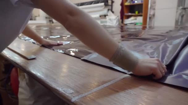 Una mujer corta película de PVC en la tienda para la producción de techos tensados — Vídeos de Stock